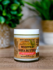 Jar of Mion Artisan Soap Whipped Shea Butter Pink Grapefruit on a wooden surface with a blurred green plant in the background.