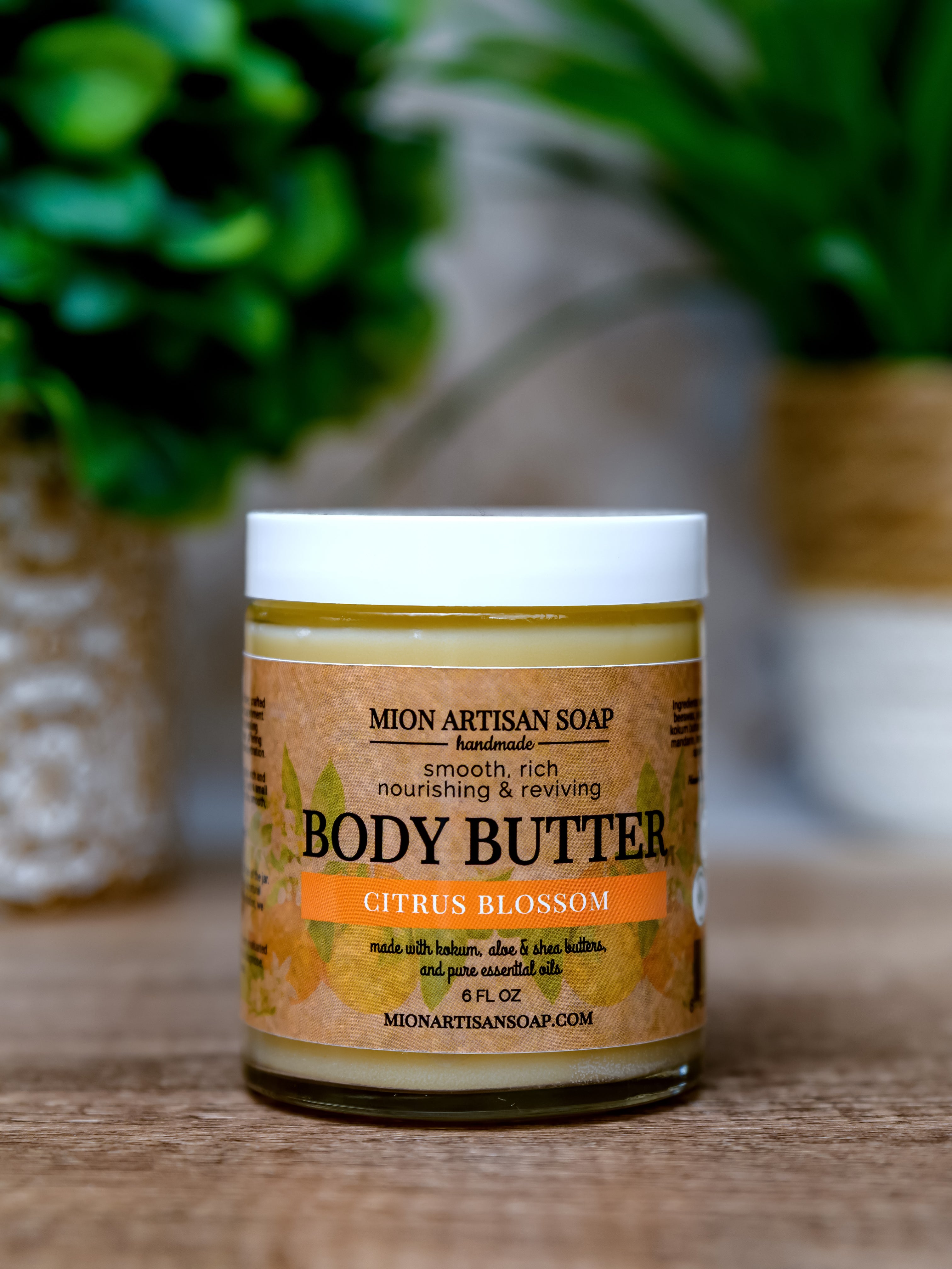 Jar of Mion Artisan Soap body butter with a blurred green plant in the background