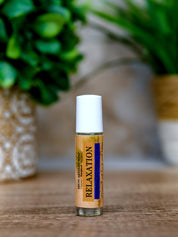 Roll-on bottle labeled 'Relaxation' on a wooden surface with greenery in the background