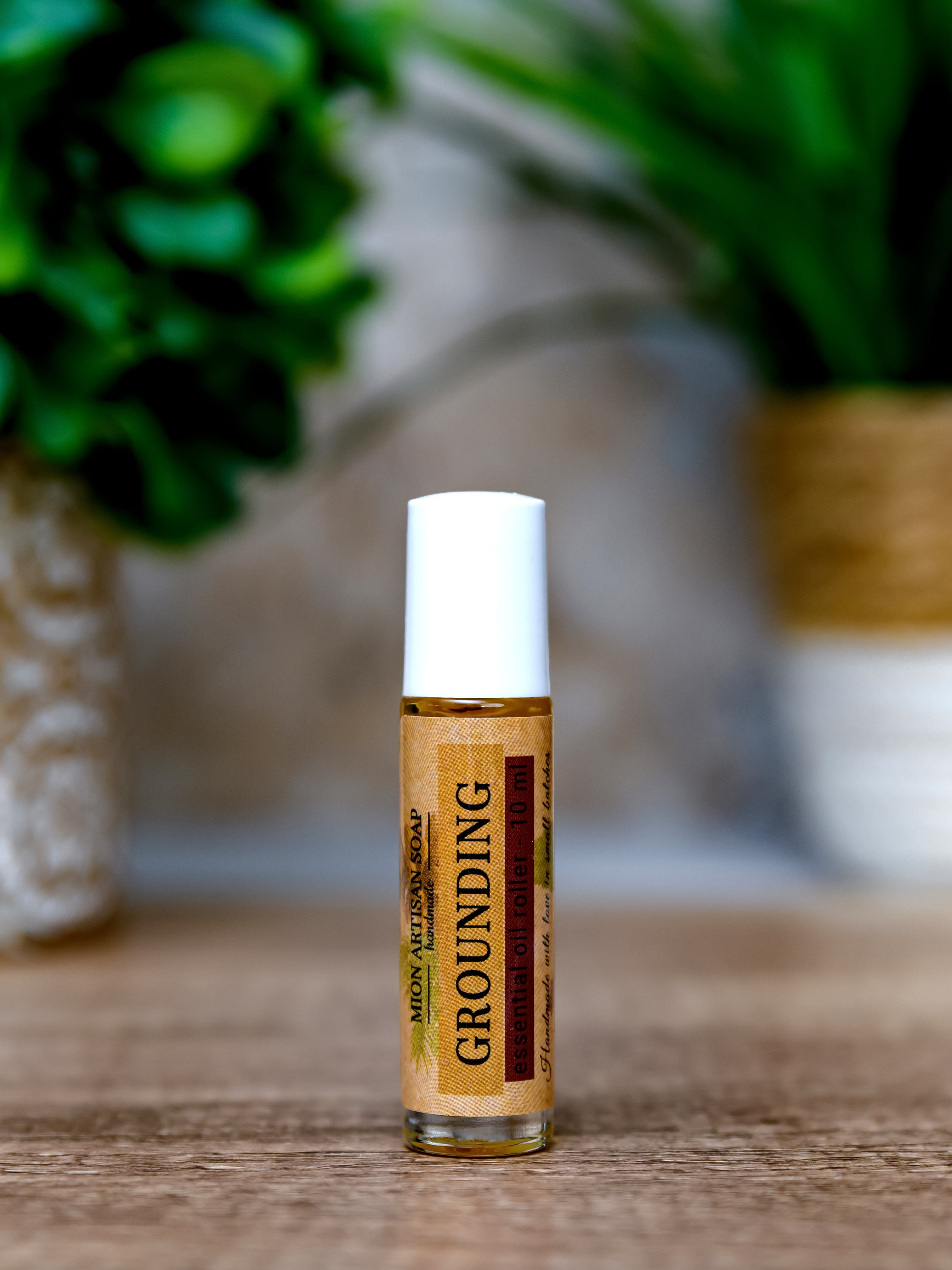 Roll-on bottle labeled 'Grounding' on a wooden surface with a blurred natural background