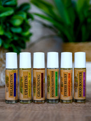 Set of six essential oil roller bottles with labels on a wooden surface.