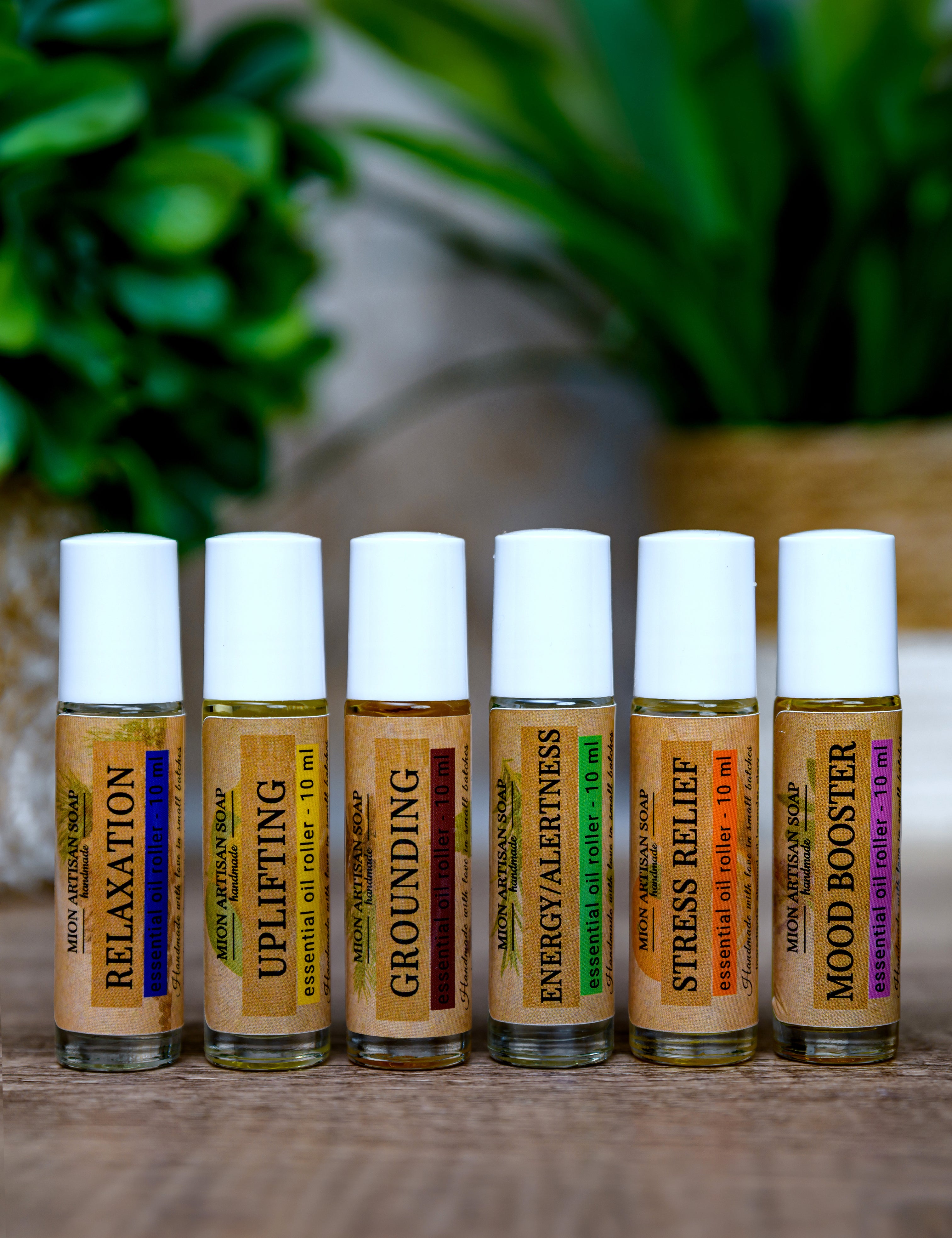 Set of six essential oil roller bottles with labels on a wooden surface.