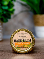 Hand balm container with 'Mion Artisan Soap' label on a wooden surface.